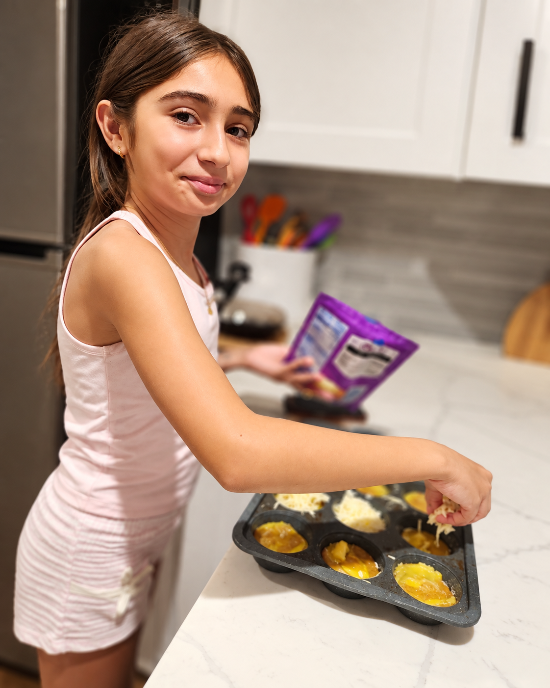 Young cook adding ingredients to a muffin tray